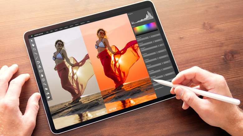 Tablet displaying a photo editing app with a side-by-side before-and-after image of a woman at the beach, as a hand uses a stylus to adjust color and exposure settings.