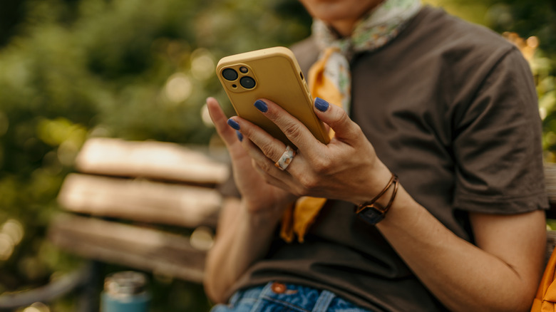 Woman sitting on a bench in a park while using her smartphone