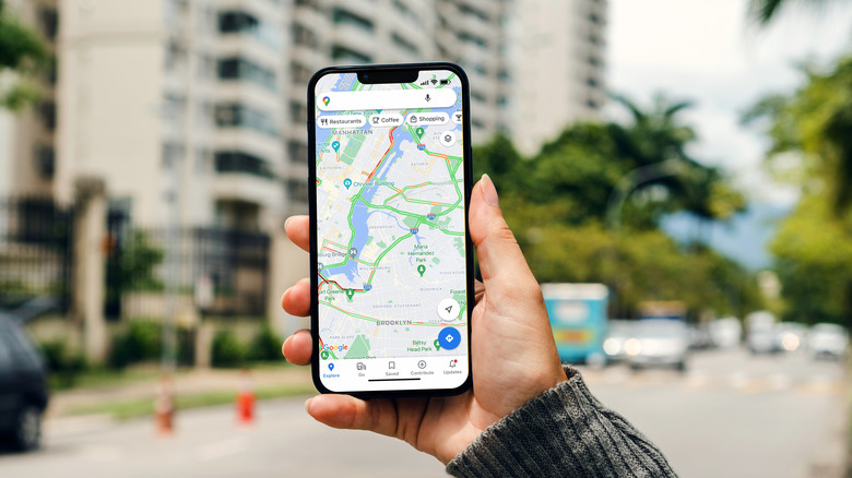 Close-up of an iPhone running the Google Maps app with a blurred cityscape background