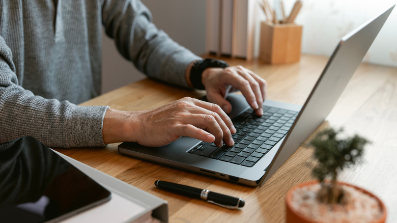 Person working on laptop on wooden table