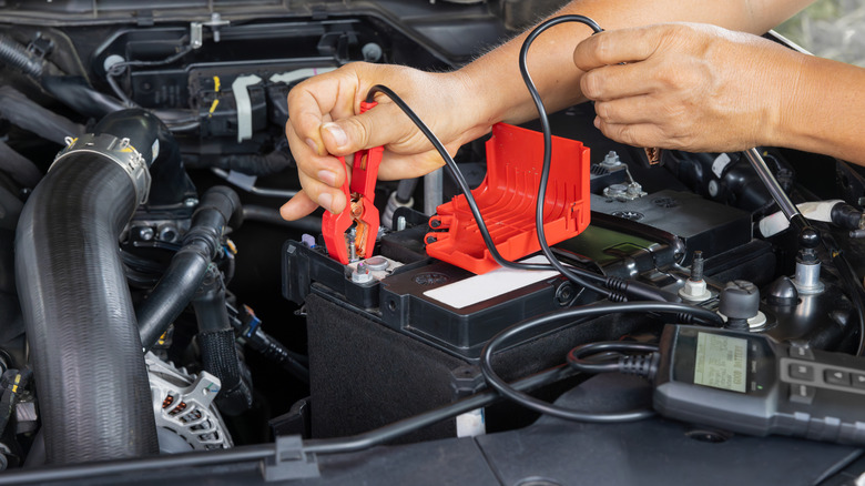 Hands attaching a tester to a car battery