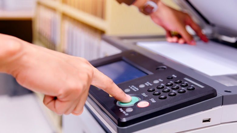 a person pressing a button on a printer