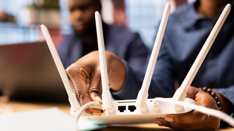 A person rebooting their Wi-Fi router by moving cables
