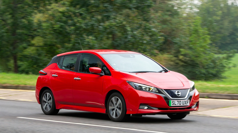 a red 2021 Nissan Leaf driving on a road