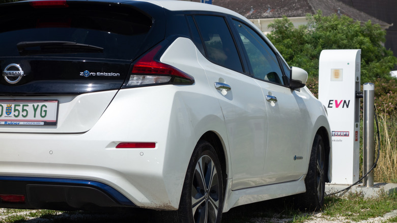a white 2021 Nissan Leaf charging at an electric car charger