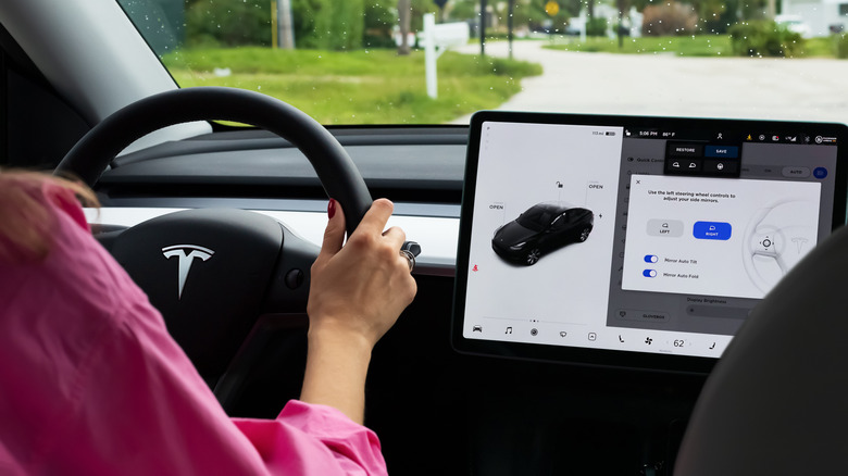 Driver interacting with the Tesla Model Y touchscreen while driving.