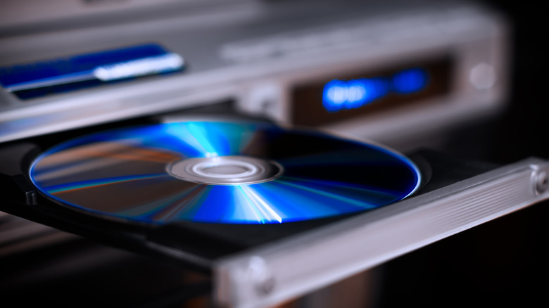 A DVD being inserted into the disc tray of a DVD player.