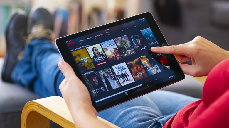 A person outside with an iPad on their lab looking at the Netflix app.