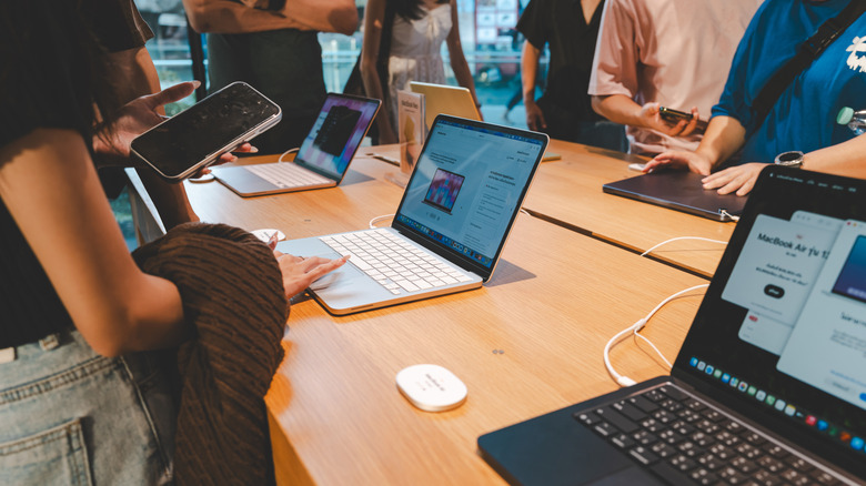 A group of customers explore and test the features of the new MacBook Neo at Apple Store.