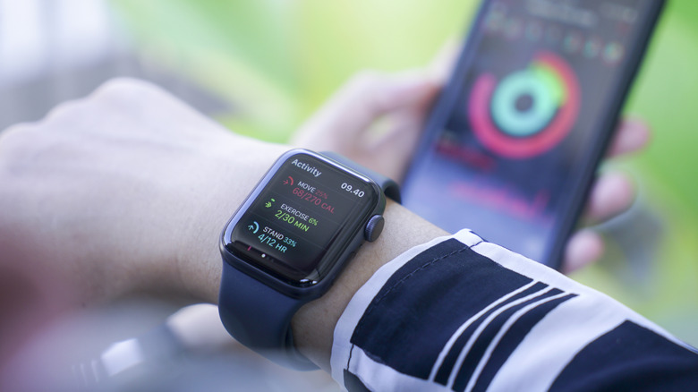 An Apple Watch on a person's wrist with a phone in the background