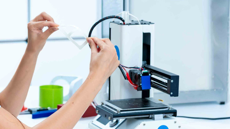 A person working with a 3D printer on a table or bench