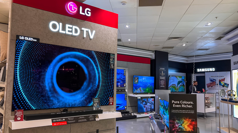 An LG OLED TV mounted on a wall in the TV section of an electronics store