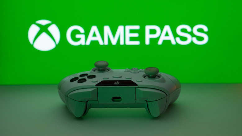 A white controller sitting in front of the Xbox Game Pass logo.