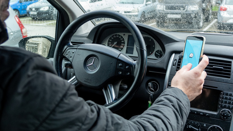 Person setting up the Waze app in their car on a phone mounted to the dashboard.