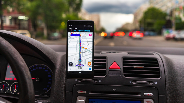 Waze navigation shown on a phone mounted on a car dashboard