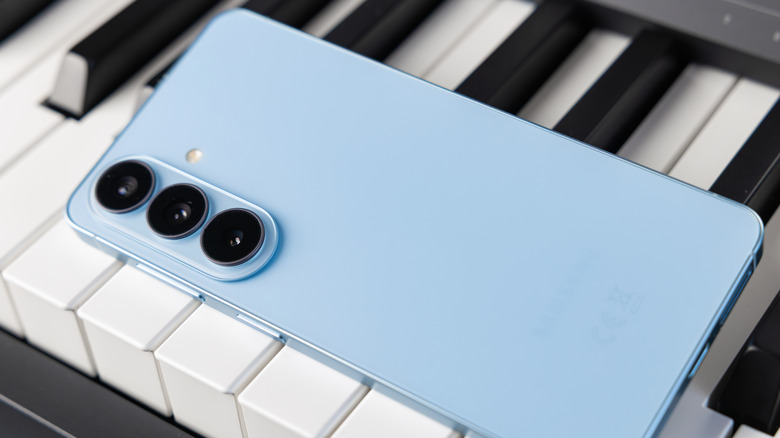 Close-up of a Sky Blue Samsung Galaxy S26 displayed on top of a piano.