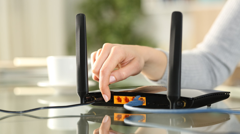 A hand on the back of a modem.