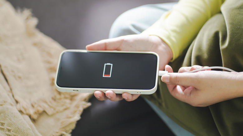 a person plugging a phone with a dying battery into charge