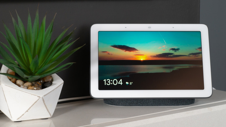 Google Nest Hub smart display on a shelf with a plant nearby