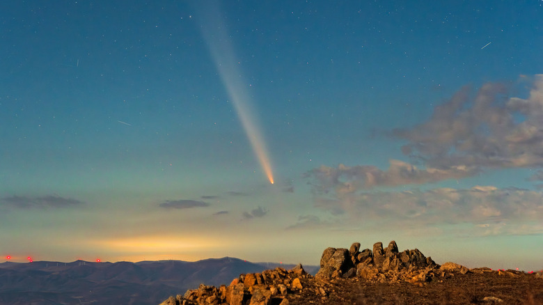 A meteor streaks through a starry sky over mountains