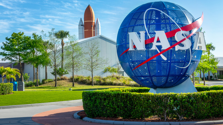 NASA logo at Kennedy Space Center with facility in the background