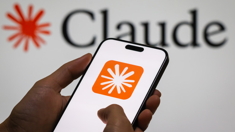 a person holding a phone with Claude AI symbol displayed next to a white background with 'Claude' on it