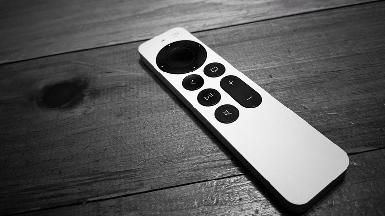 An Apple TV remote against a gray wooden background