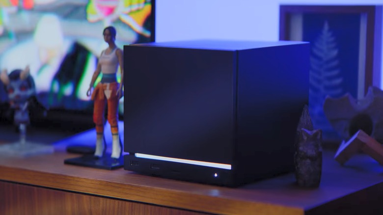 Black Steam Machine on a desk next to statue of Chell from Portal 2