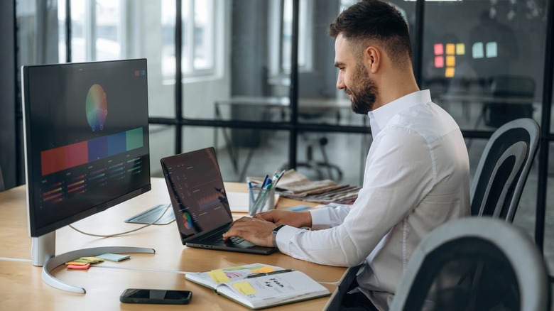 A man working on a laptop connected to an external monitor