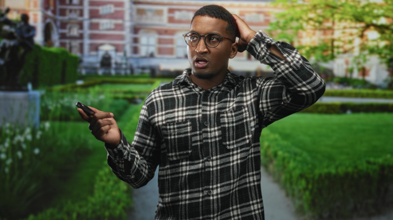 A man holding a car key fob while looking confused.