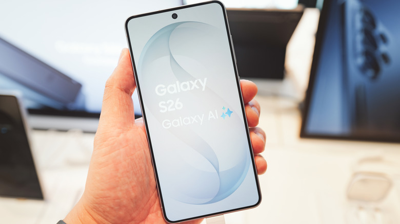 A person holding a Galaxy S26 in their hand showing the phone display on its screen the logo and Galaxy AI on it