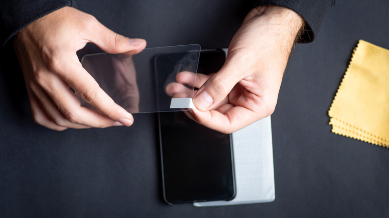 Someone getting ready to apply a screen protector to the front of their smartphone.