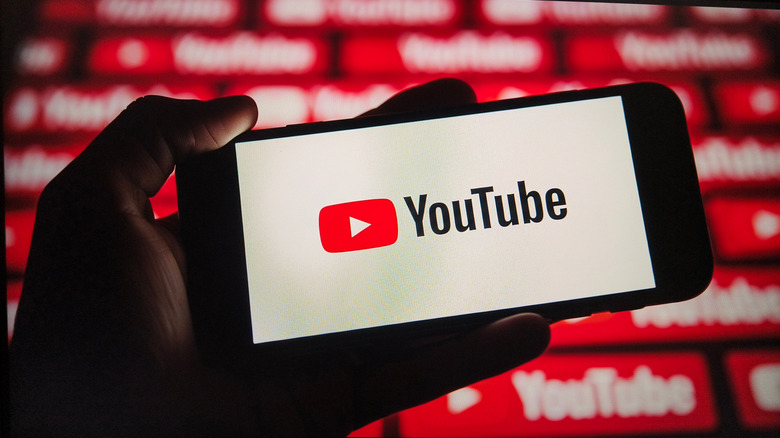 Close-up of a hand holding a smartphone displaying the YouTube logo