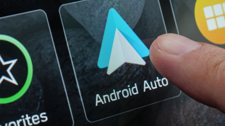 person tapping Android Auto button in car