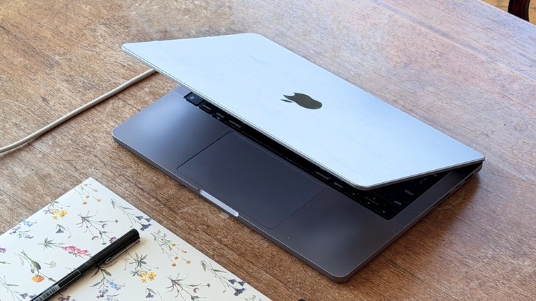 A half-closed MacBook Pro on a wooden table