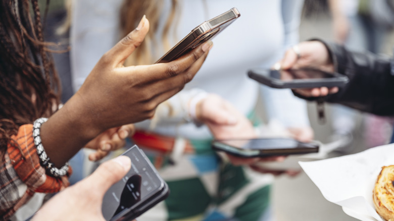 a group of friends all holding smartphones