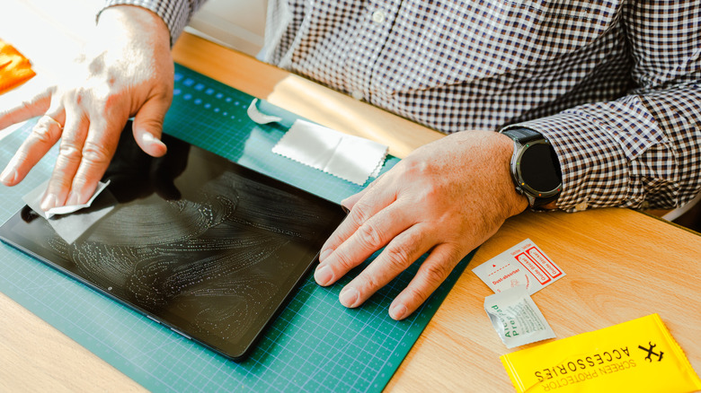 Close-up of hands cleaning a tablet screen before applying a new screen protector