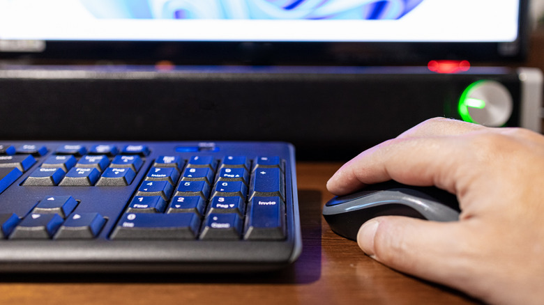 Close up of a soundbar at a desk with someone using their mouse and keyboard.