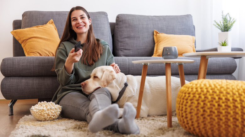 woman watching TV in her living room with her dog