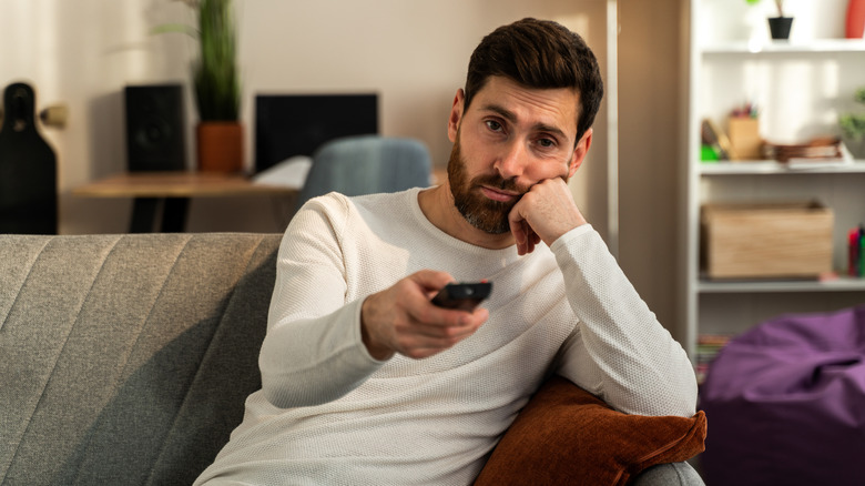 a man watching TV and bored by all the ads