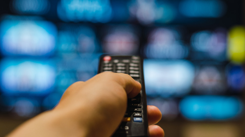a hand pointing a remote toward a TV