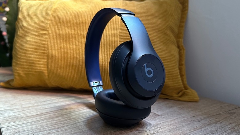 Beats Studio Pro headphones on a desk with a yellow cushion behind them