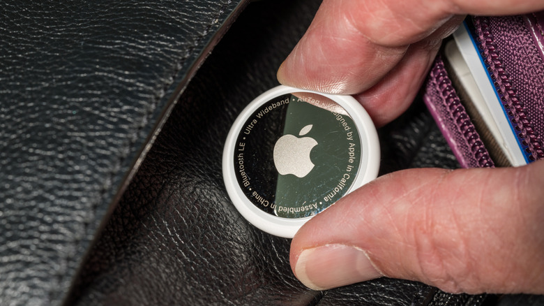 Airtag being slipped into the pocket of a bag and concealed.