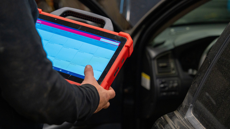 Technician using a tablet car scanning tool to diagnose issues.