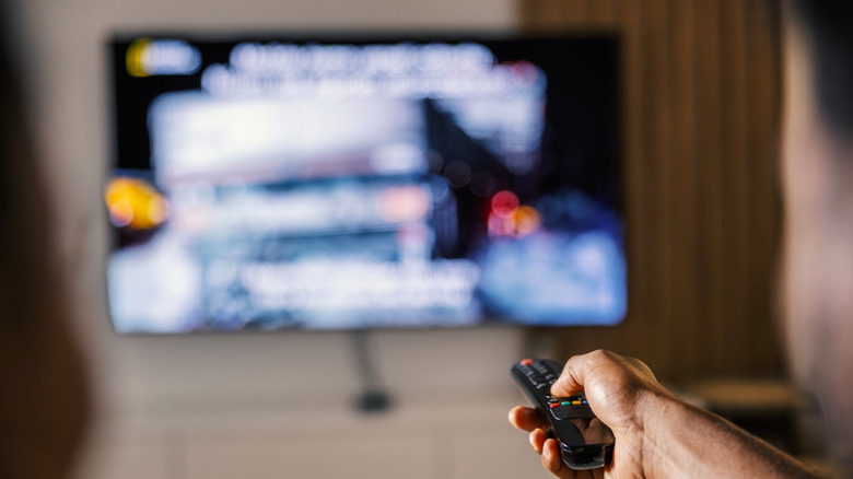 hand holding a remote with a smart tv blurred in background