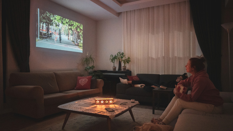Family watching projected media on a wall.