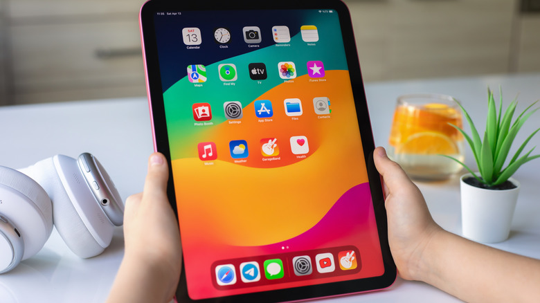 Two hands holding an iPad vertically on a kitchen counter.