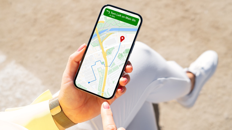 A woman sitting down holding a phone showing directions from Google Maps.