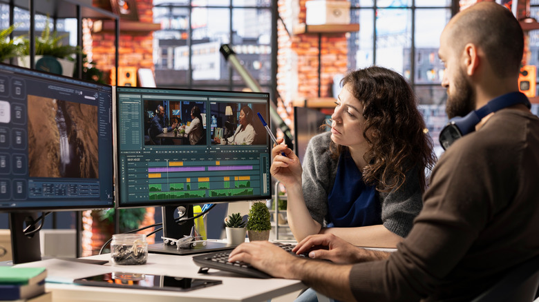 Two people sitting at a video editing computer