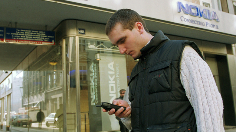 A man typing a number into his '90s-era Nokia cellphone.